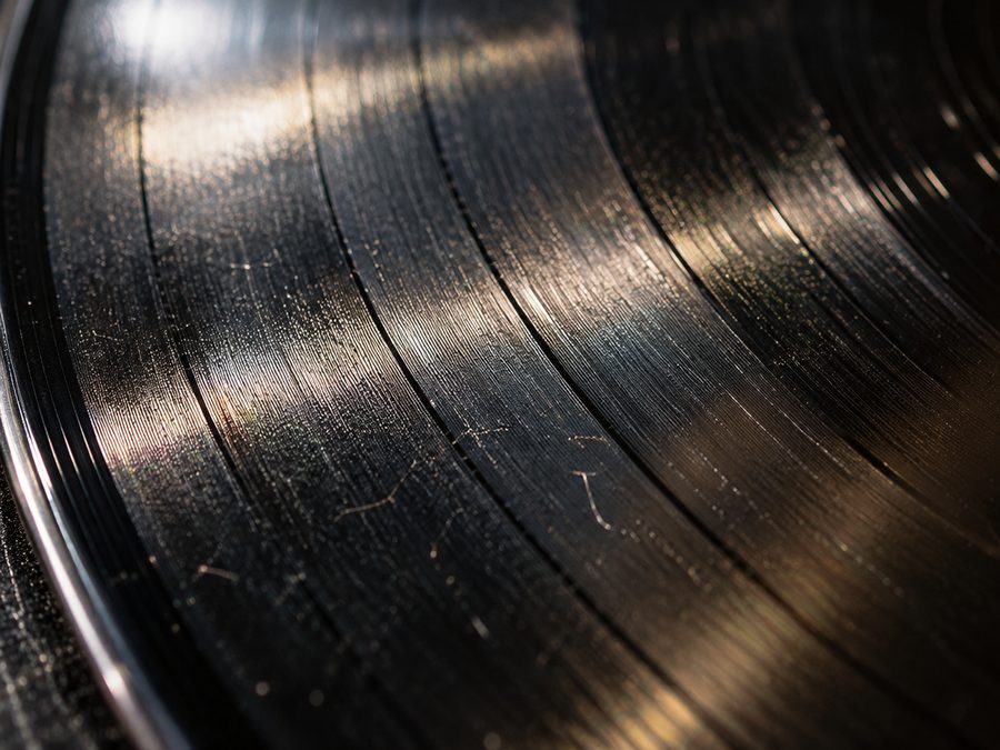 Primer plano de la superficie de un disco de vinilo con rayas finas visibles bajo la luz.